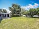 Spacious backyard with mature trees surrounding a lush lawn and a screened-in patio for outdoor enjoyment at 3271 36Th N St, St Petersburg, FL 33713