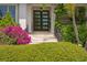 Close-up of the front door, surrounded by lush greenery and colorful flowers enhancing the home's curb appeal at 4807 W Longfellow Ave, Tampa, FL 33629