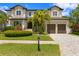 Stately two-story home featuring a manicured front lawn, mature trees, a brick driveway, and a two-car garage at 4807 W Longfellow Ave, Tampa, FL 33629