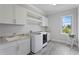 Clean and organized laundry room with white cabinetry, a sink, and a window at 4807 W Longfellow Ave, Tampa, FL 33629