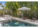 Swimming pool surrounded by lush landscaping, lounge chairs, and comfortable seating under a pergola at 4807 W Longfellow Ave, Tampa, FL 33629