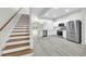 Open-concept kitchen and staircase featuring white cabinets, stainless steel appliances, and light gray flooring at 4910 Chatham Gate Dr, Riverview, FL 33578