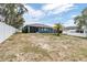 View of the home's back exterior and backyard, featuring mature trees and a white fence at 5540 Applegate Dr, Spring Hill, FL 34606