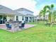 Large backyard with a brick patio, fire pit, outdoor kitchen, and mature palms at 6118 Voyagers Pl, Apollo Beach, FL 33572