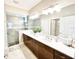 Lovely main bathroom boasts double sinks, granite countertops, and tiled shower with a glass door at 6118 Voyagers Pl, Apollo Beach, FL 33572