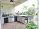 Covered outdoor kitchen with bar seating, stainless steel grill and stone accents at 6118 Voyagers Pl, Apollo Beach, FL 33572