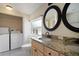 Bathroom featuring double vanity, granite counters, laundry closet, and ample storage space at 6419 S Englewood Ave, Tampa, FL 33611