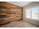 Cozy bedroom with a statement wood wall, two windows, and wood-look flooring at 6419 S Englewood Ave, Tampa, FL 33611
