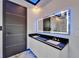 Modern bathroom featuring a dual sink vanity with granite counters, a backlit mirror, and a sleek door at 6520 Simone Shores Cir, Apollo Beach, FL 33572