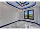 Modern bedroom features a tray ceiling with LED lighting and a ceiling fan with marble floors and a large window at 6520 Simone Shores Cir, Apollo Beach, FL 33572