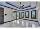 Modern bedroom features a tray ceiling with LED lighting, marble floors, and three windows plus sliding doors at 6520 Simone Shores Cir, Apollo Beach, FL 33572