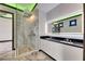 Modern bathroom with a glass-enclosed shower, dual sinks, backlit mirror and stylish black and white finishes at 6526 Simone Shores Cir, Apollo Beach, FL 33572