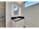 Modern bathroom vanity with black countertop and illuminated mirror at 6526 Simone Shores Cir, Apollo Beach, FL 33572
