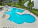 Aerial view of a uniquely shaped community swimming pool with lounge chairs, hot tub, and lakeside views at 6918 Potomac Cir, Riverview, FL 33578