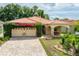 Charming single-Gathering home featuring a tile roof, arched entryway, and attached two-car garage at 6928 Cozumel Ct, Land O Lakes, FL 34637