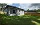 Side exterior view of home featuring well-kept backyard with wood fence and covered patio with ceiling fan at 7011 N 15Th St, Tampa, FL 33610