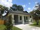 Attractive home featuring gray brick-like accents, a covered porch, and complemented by lush green landscaping at 7011 N 15Th St, Tampa, FL 33610