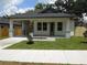 Charming single-story home with a welcoming front porch, landscaped lawn, and modern design elements at 7011 N 15Th St, Tampa, FL 33610