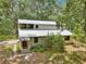 Two-story home featuring a metal roof surrounded by mature trees and lush landscaping at 7189 Griffin Rd, Brooksville, FL 34601