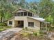 Tan colored house with a driveway going into a covered carport surrounded by trees at 7189 Griffin Rd, Brooksville, FL 34601