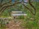 Secluded two-story home with a metal roof nestled among mature trees and a lush landscape at 7189 Griffin Rd, Brooksville, FL 34601