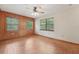 Living room with wood-paneled accent wall, tile floors, ceiling fan, and windows that provide natural light at 7189 Griffin Rd, Brooksville, FL 34601