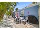 Outdoor patio with outdoor dining, BBQ and blue cottage with pink door surrounded by palms at 722 Gulf Blvd, Indian Rocks Beach, FL 33785