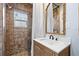 Bathroom featuring a brown tiled shower, wooden vanity with sink, and an ornate mirror with view to bedroom at 722 Gulf Blvd, Indian Rocks Beach, FL 33785