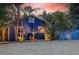 Charming blue home with tropical landscaping and a white picket fence at 722 Gulf Blvd, Indian Rocks Beach, FL 33785