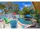 Blue pool is surrounded by lounge chairs, palm trees, and a white picket fence, perfect for relaxation at 722 Gulf Blvd, Indian Rocks Beach, FL 33785