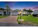 Charming single-story home featuring a brick driveway, well-manicured lawn, and tasteful landscaping at 746 Masterpiece Dr, Sun City Center, FL 33573