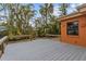 Grey wood deck surrounded by trees and an orange home exterior at 819 Gulf Blvd, Indian Rocks Beach, FL 33785