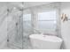 Bright bathroom featuring glass shower, free-standing tub, and elegant marble tile at 8518 Tidal Bay Ln, Tampa, FL 33635