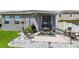 A backyard patio with an outdoor dining and lounge area, surrounded by decorative stones and green landscaping at 9577 Sandy Bluffs Cir, Parrish, FL 34219