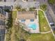 Aerial view of community pool with blue sunshades, lounge chairs, manicured lawn, and mature trees at 960 Starkey Rd # 2405, Largo, FL 33771