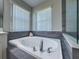 Bright bathroom featuring a soaking tub with grey tiling and a large seashell accessory at 9814 Palazzo St, Seffner, FL 33584