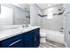 Bathroom featuring marble tiled shower, a blue accent stripe, and a blue vanity with marble countertop at 9909 San Mateo Way, Port Richey, FL 34668