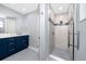 Stylish bathroom showcasing a marble-tiled shower, vanity with blue cabinets and unique flooring at 9909 San Mateo Way, Port Richey, FL 34668