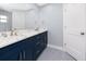 Elegant bathroom featuring a large mirror, double sinks, marble countertops, and blue cabinets at 9909 San Mateo Way, Port Richey, FL 34668