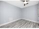 Neutral bedroom showcasing gray wood-look floors, light-blue painted walls, and modern ceiling fan at 9909 San Mateo Way, Port Richey, FL 34668