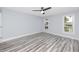 A sunlit bedroom highlighting wood-look floors, two windows with backyard views, and light-blue walls at 9909 San Mateo Way, Port Richey, FL 34668