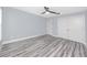 Spacious bedroom showcasing light-blue walls, modern ceiling fan, and double door closet with hardwood flooring at 9909 San Mateo Way, Port Richey, FL 34668