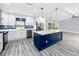 Modern kitchen features an eat-in island, stainless steel appliances, quartz countertops, and blue tiled backsplash at 9909 San Mateo Way, Port Richey, FL 34668