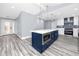 Beautiful kitchen featuring gray wood flooring, a navy island with a built-in microwave, and marble countertops at 9909 San Mateo Way, Port Richey, FL 34668