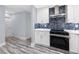 Modern kitchen featuring white cabinets, quartz countertops, stainless steel appliances, and blue tiled backsplash at 9909 San Mateo Way, Port Richey, FL 34668
