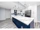 Bright kitchen featuring white cabinets, stainless appliances, navy blue island with quartz countertops, and modern pendant lights at 9909 San Mateo Way, Port Richey, FL 34668