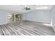 Bright and open living room with sleek flooring, a ceiling fan, and large glass sliding doors to the outdoors at 9909 San Mateo Way, Port Richey, FL 34668