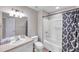 Bright bathroom features a shower-tub combo with tile surround, patterned shower curtain, and modern fixtures at 10217 Westpark Preserve Blvd, Tampa, FL 33625