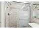 Bathroom shower featuring tile walls, glass door, and shelving at 10387 Majestic Dr, Largo, FL 33774
