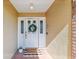Inviting front entrance featuring a decorative wreath, charming doormat, and brick accents at 10387 Majestic Dr, Largo, FL 33774